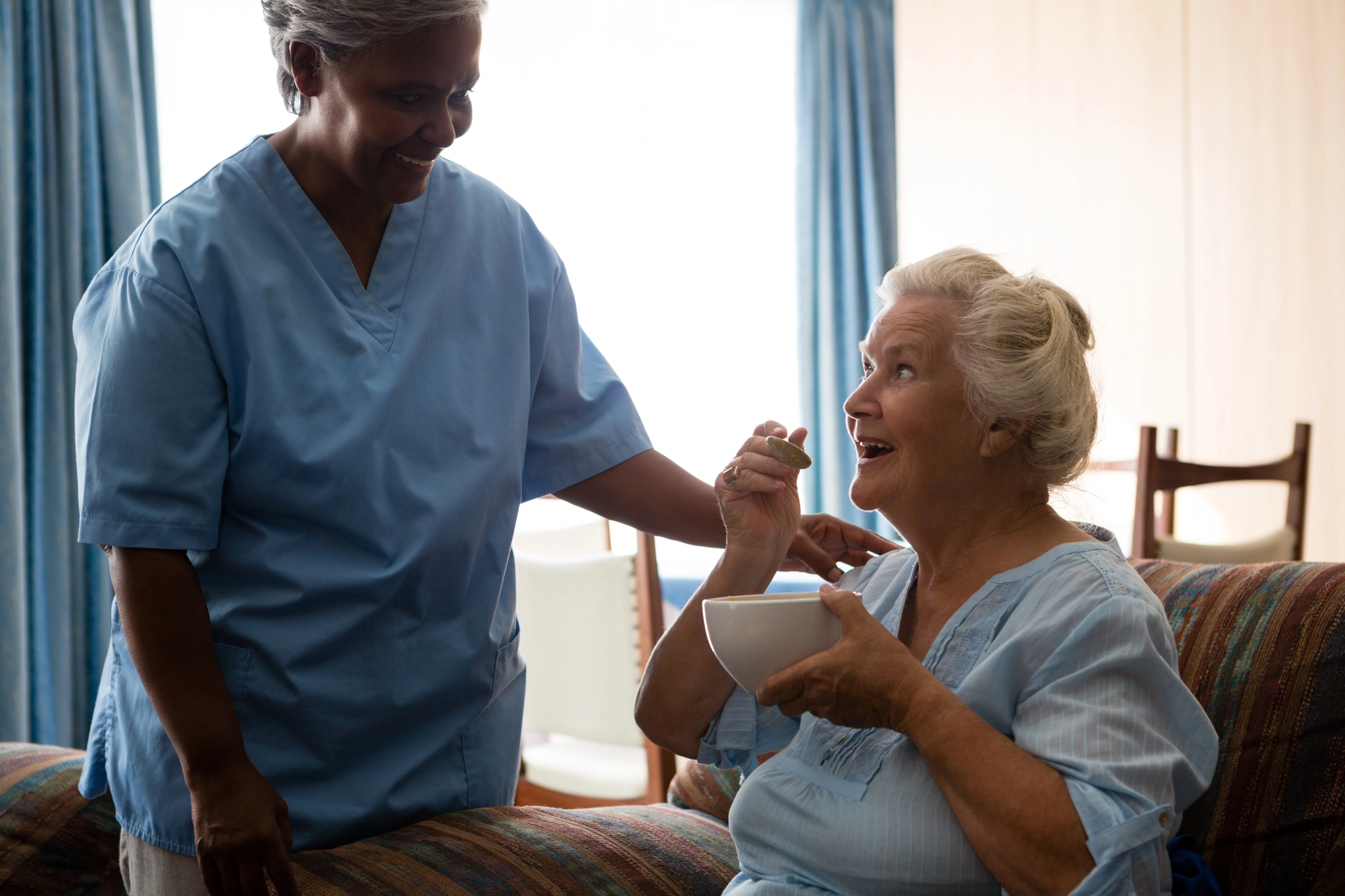 Caregiver helping elderly woman eat breakfast during in-home personal care.