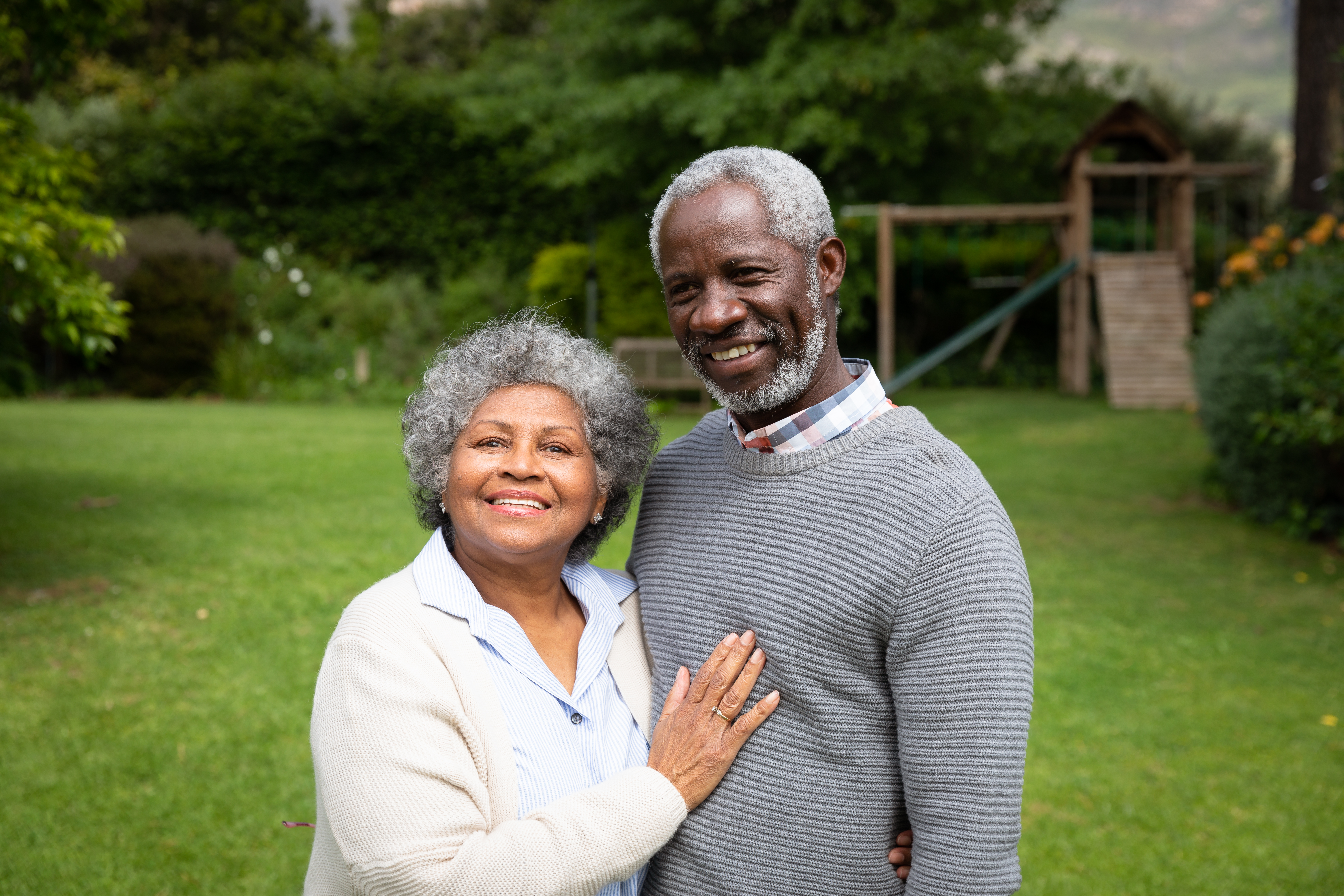Happy senior couple standing together in a garden, representing safety, independence, and well-being in aging.